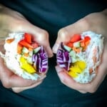 A rice paper roll split in half to show the fresh vegetables, rice noodles, and shrimp on the inside.