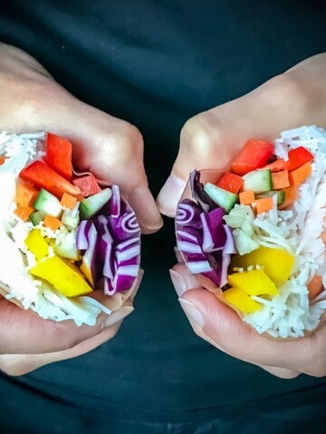 A rice paper roll split in half to show the fresh vegetables, rice noodles, and shrimp on the inside.