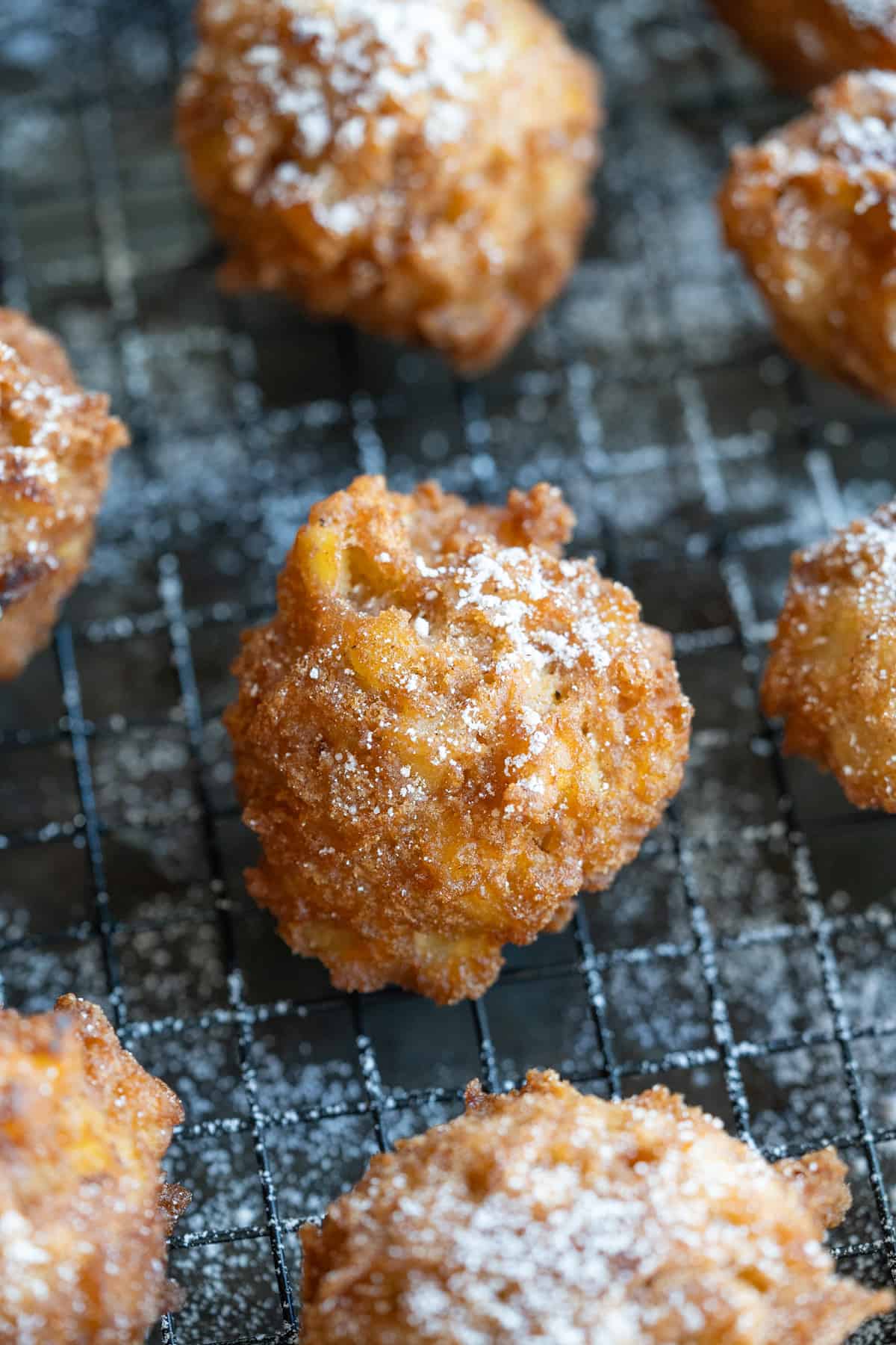 A gluten free apple fritter with a perfect crispy golden crust and powdered sugar on top.