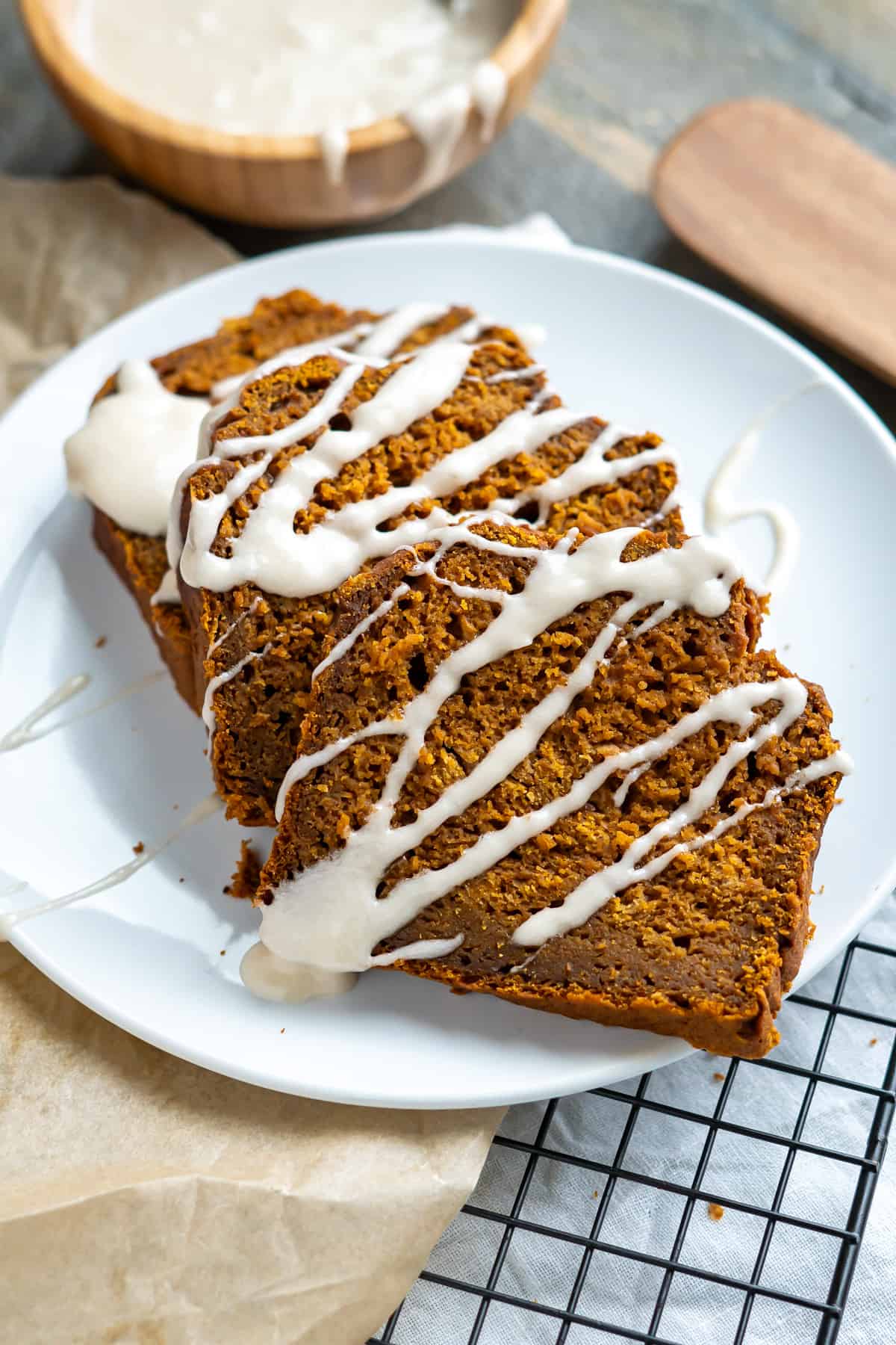 Three slices of gluten free pumpkin bread drizzled with icing on a plate.