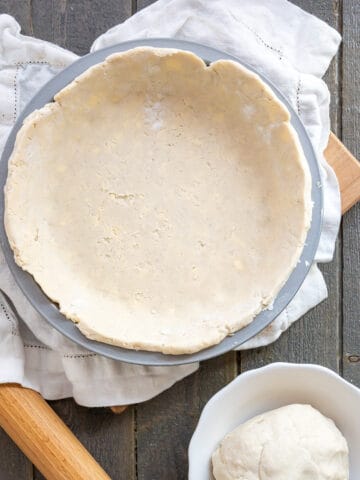 Two gluten free pie crusts, one rolled out and nestled into a pie pan and the other in a ball beside it.