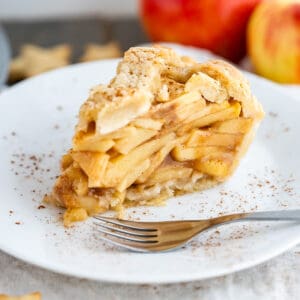 A piece of gluten free apple pie with layers of sweet gooey apple slices and a crisp buttery crust.