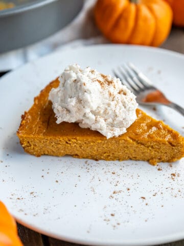 A piece of crustless pumpkin pie with whipped cream and spice on top.