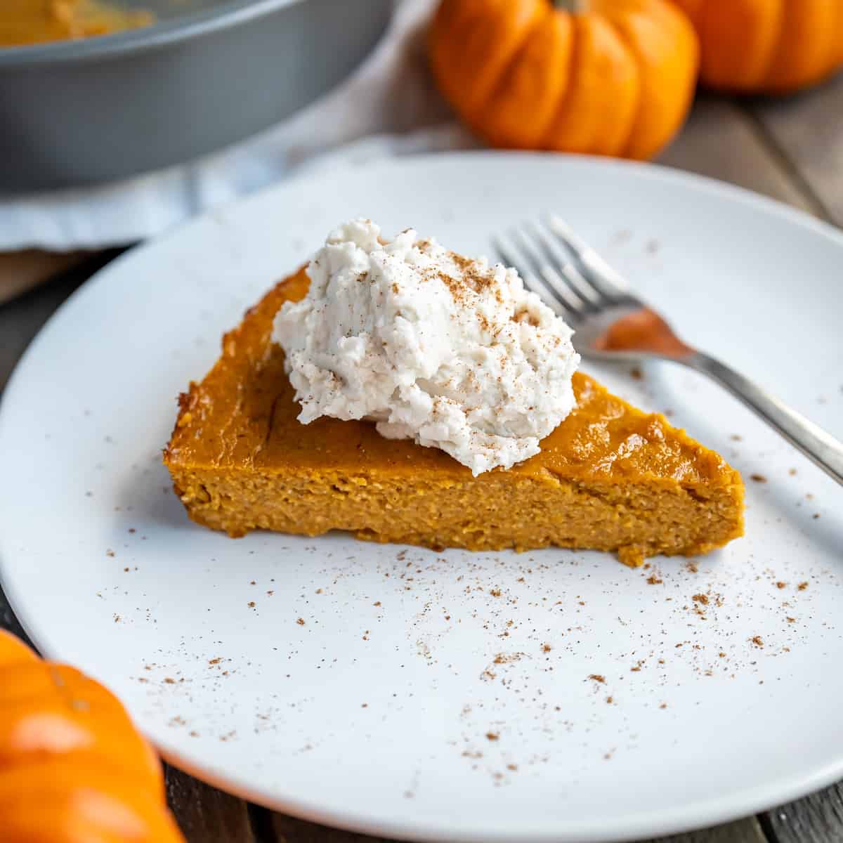 A piece of crustless pumpkin pie with whipped cream and spice on top.