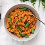 A bowl of dairy-free vodka sauce tossed with pasta and garnished with Italian parsley.