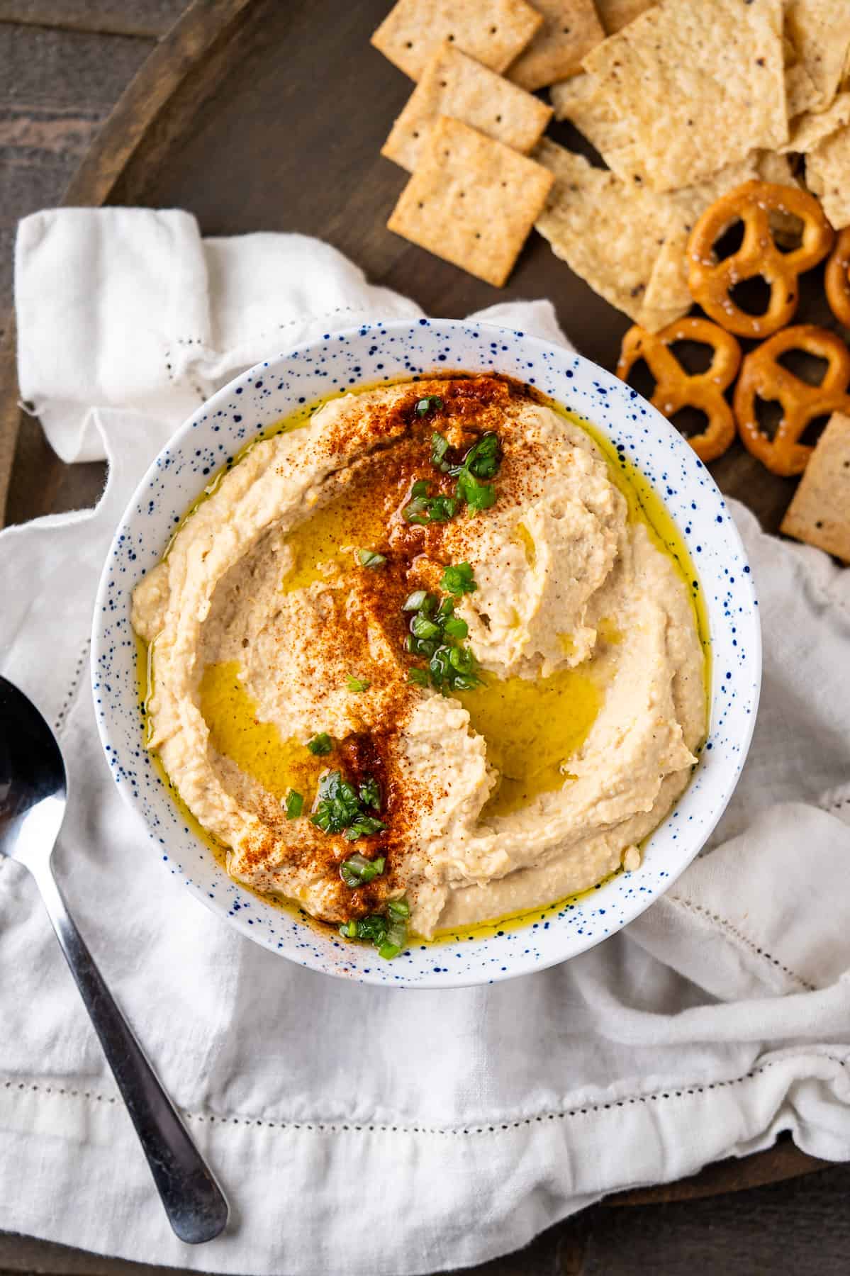 A bowl of homemade chickpea hummus with a sprinkling of paprika and chopped green onions.