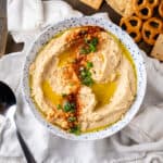 A bowl of homemade chickpea hummus with a sprinkling of paprika and chopped green onions.