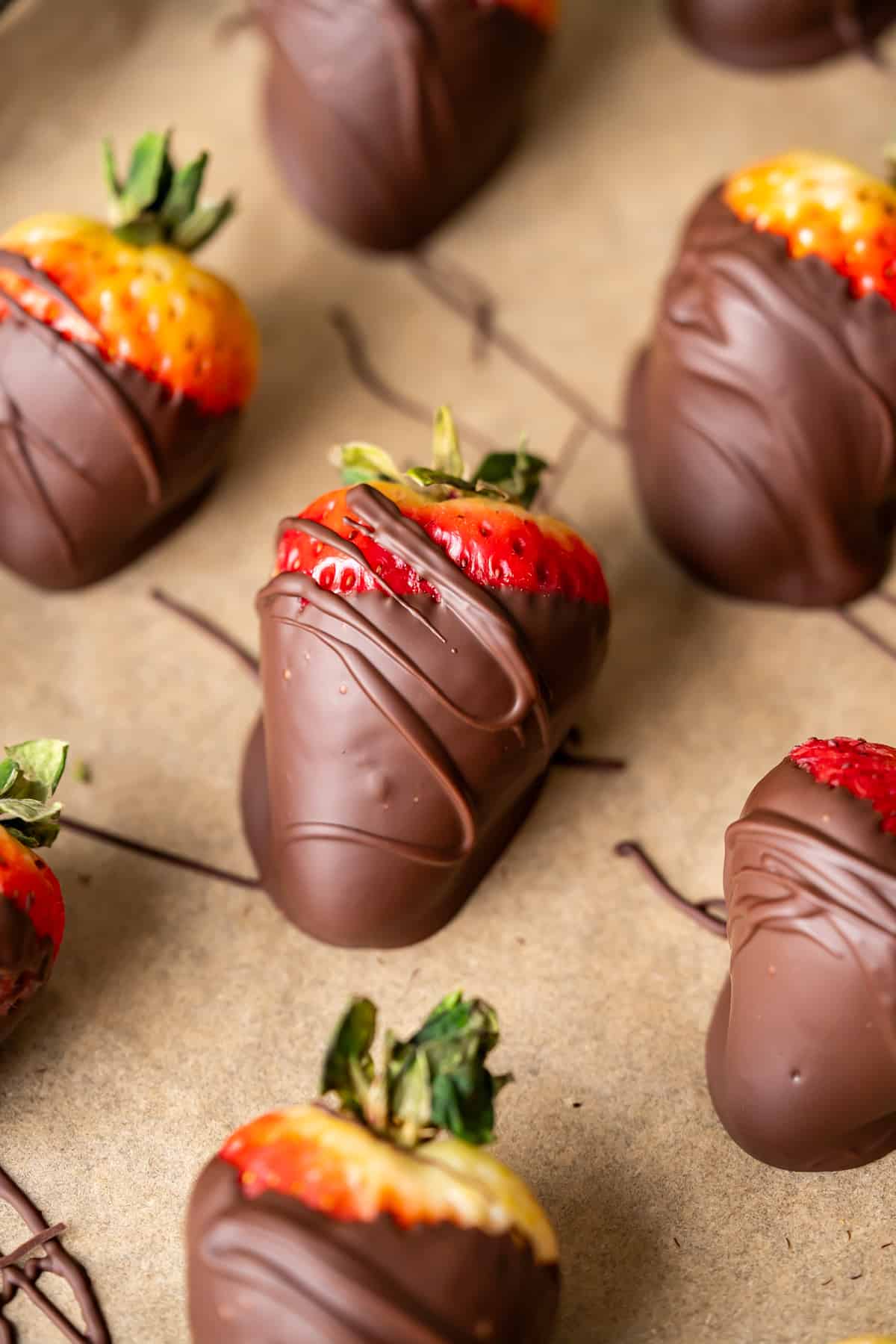 Chocolate dipped strawberries cooling on a parchment paper lined pan.