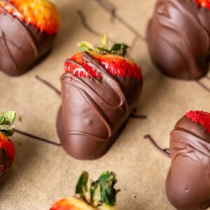 Chocolate dipped strawberries cooling on a parchment paper lined pan.