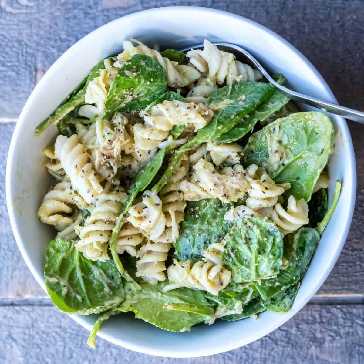 A serving bowl of Creamy Avocado Pasta with chicken and black pepper.