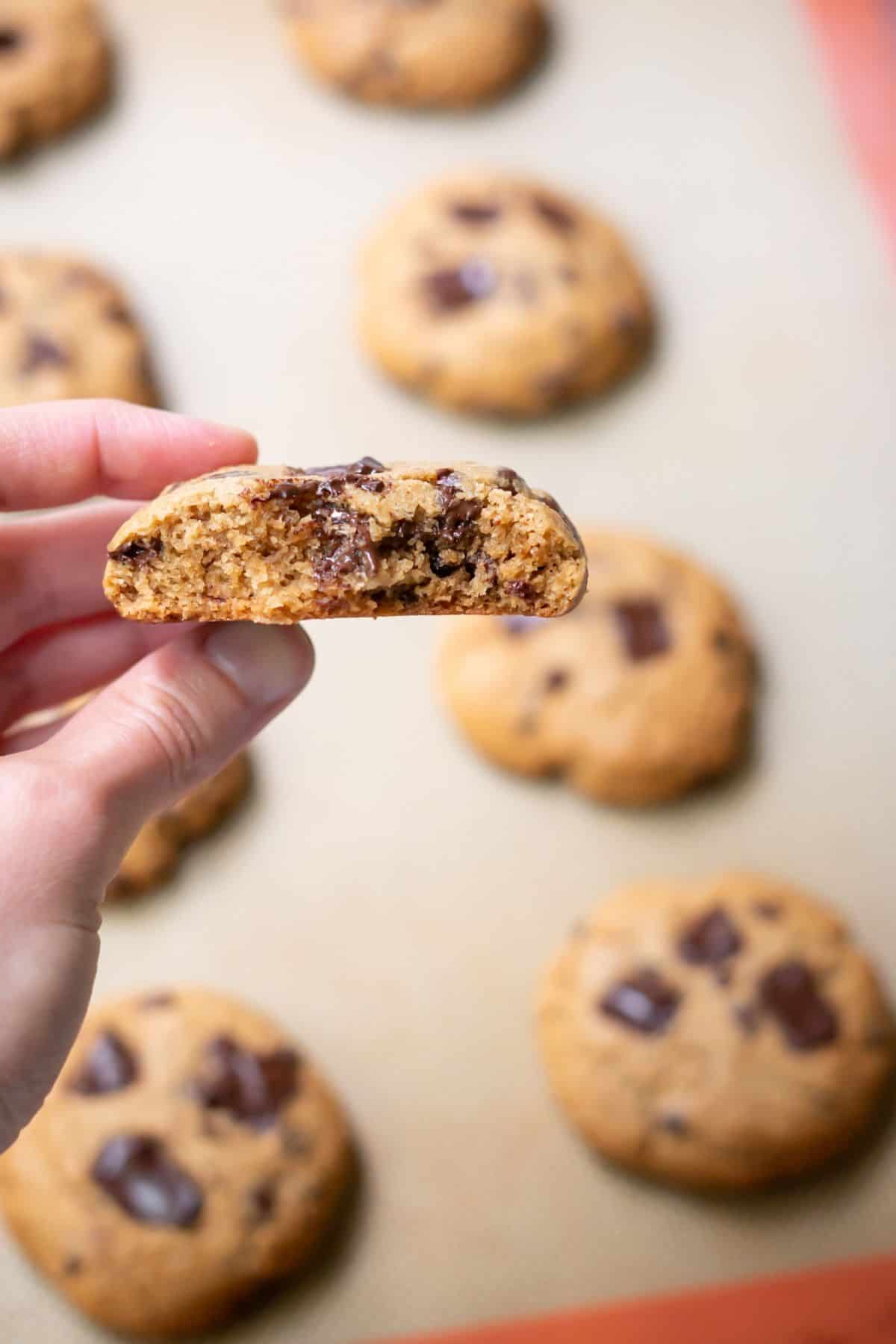 A bite taken from an almond flour chocolate chip cookie to show the traditional cookie crumb.
