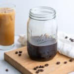 A mason jar of cold brew coffee concentrate beside a glass of concentrate turned into a cold brew with creamer.