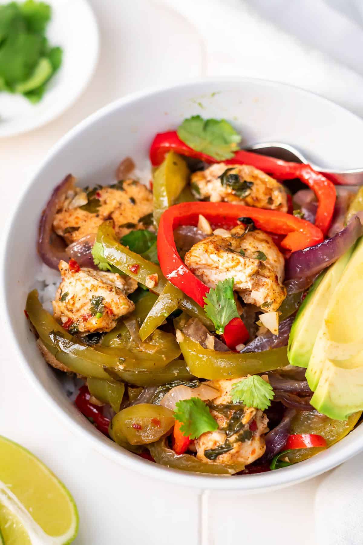 A close up of the roasted bell peppers and chicken in a chicken fajita bowl with rice.