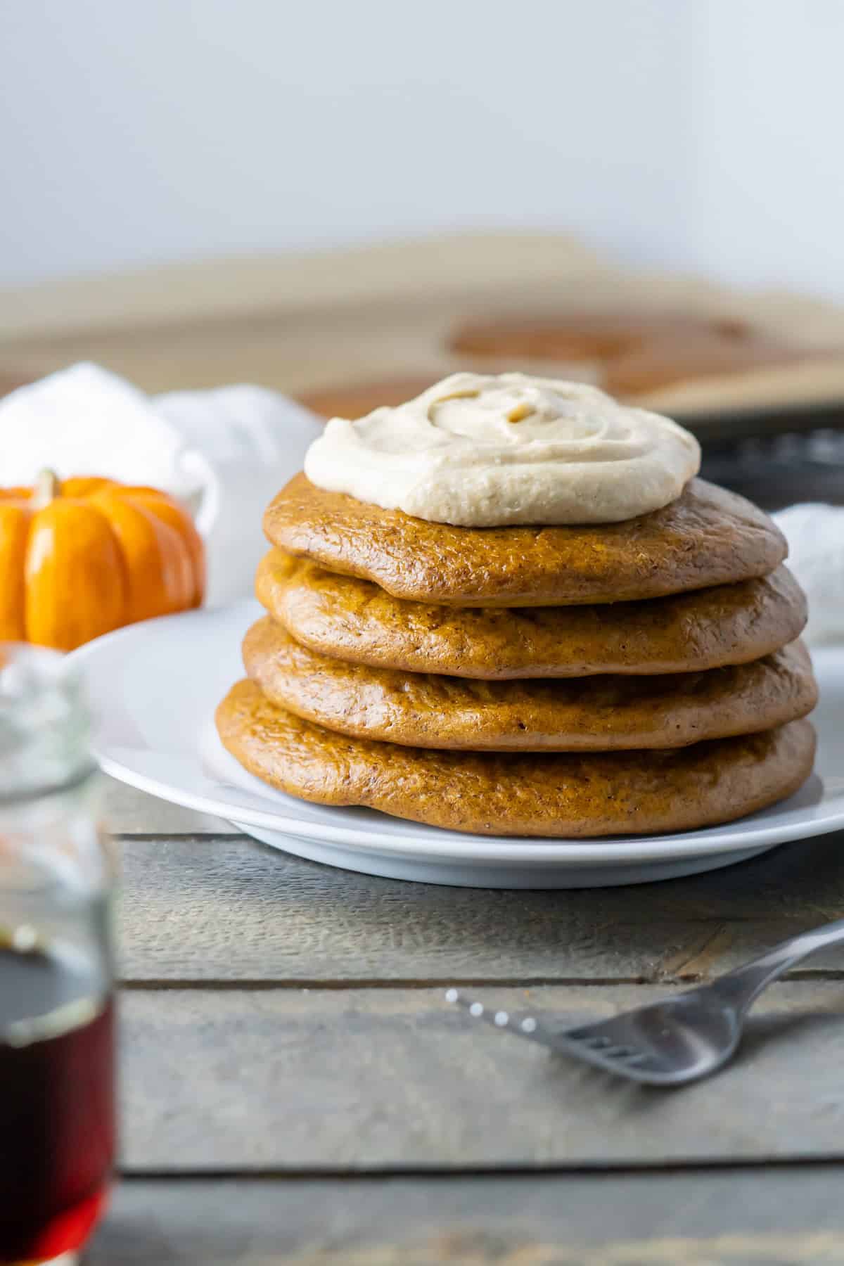 A stack of flourless pumpkin pancakes with a dollop of pumpkin spice whipped cream.