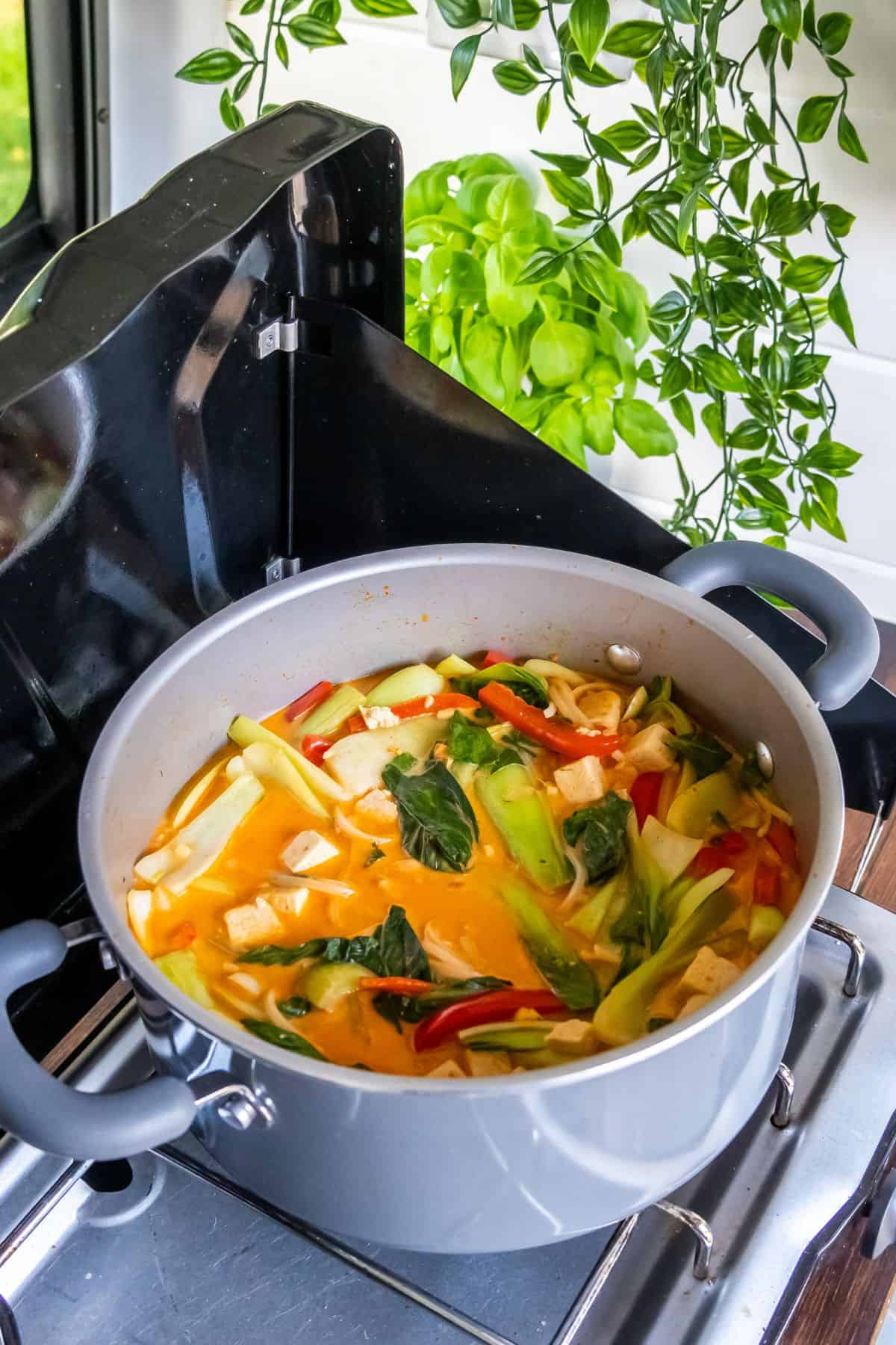 Thai coconut tofu soup cooking on a camp stove.