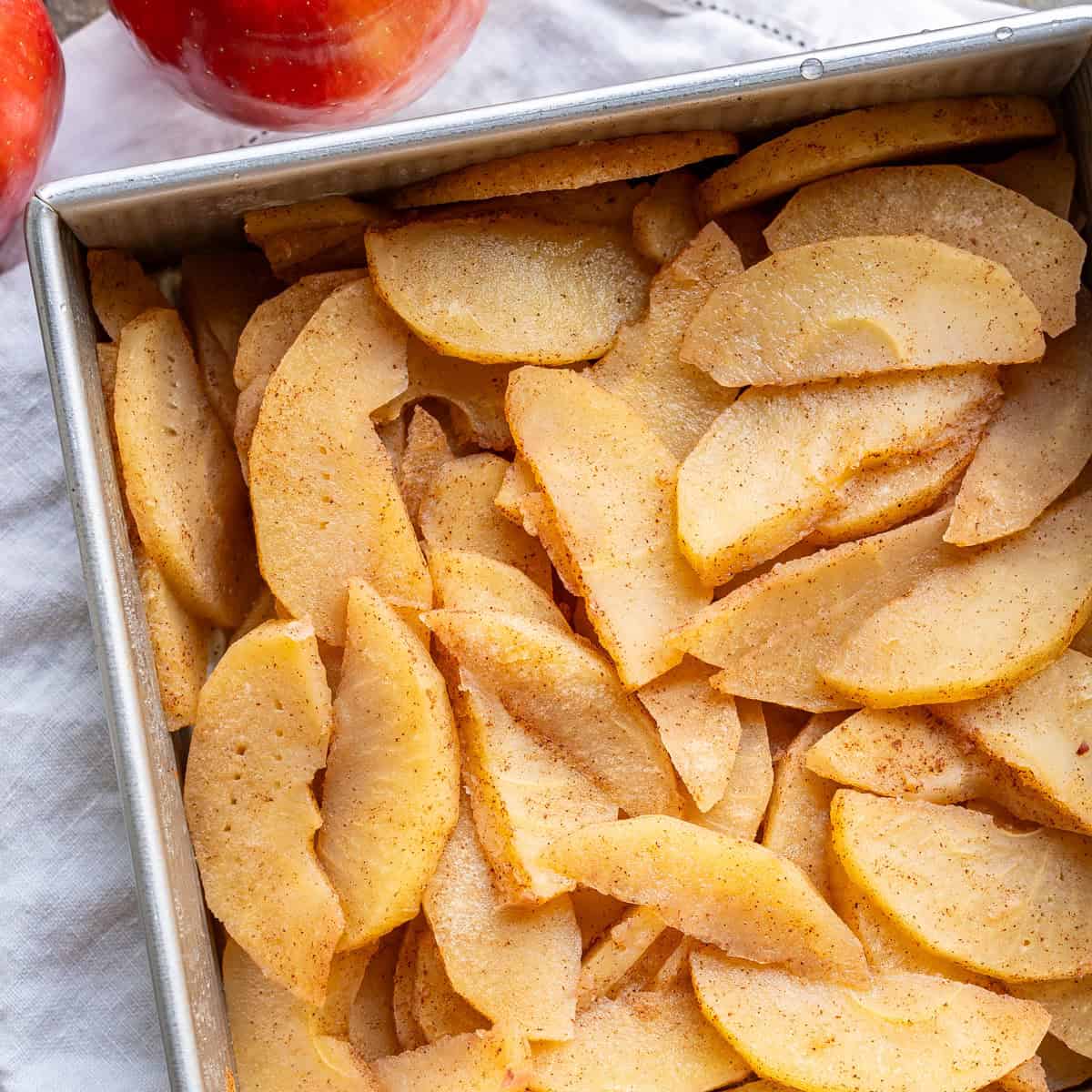 A square baking pan filled with golden baked cinnamon apple slices.