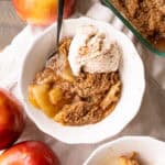 A bowl of vegan apple crumble with a crisp streusel topping and vegan ice cream.