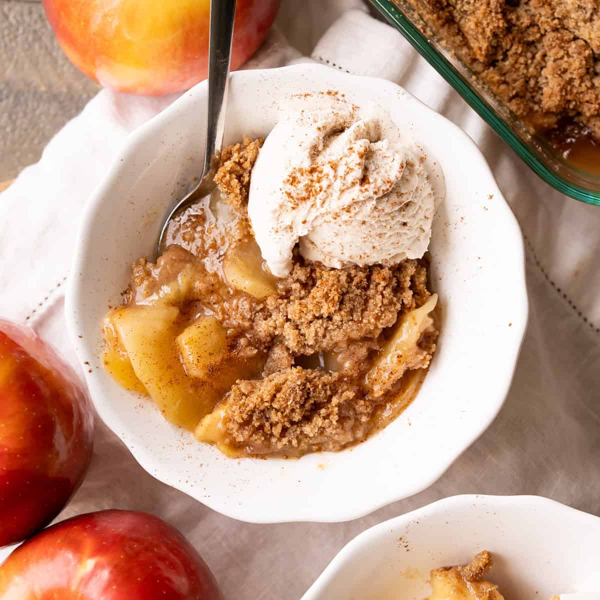 A bowl of vegan apple crumble with a crisp streusel topping and vegan ice cream.
