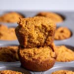 A close up of two almond flour pumpkin muffins showing the soft inner and outer textures of the muffins.