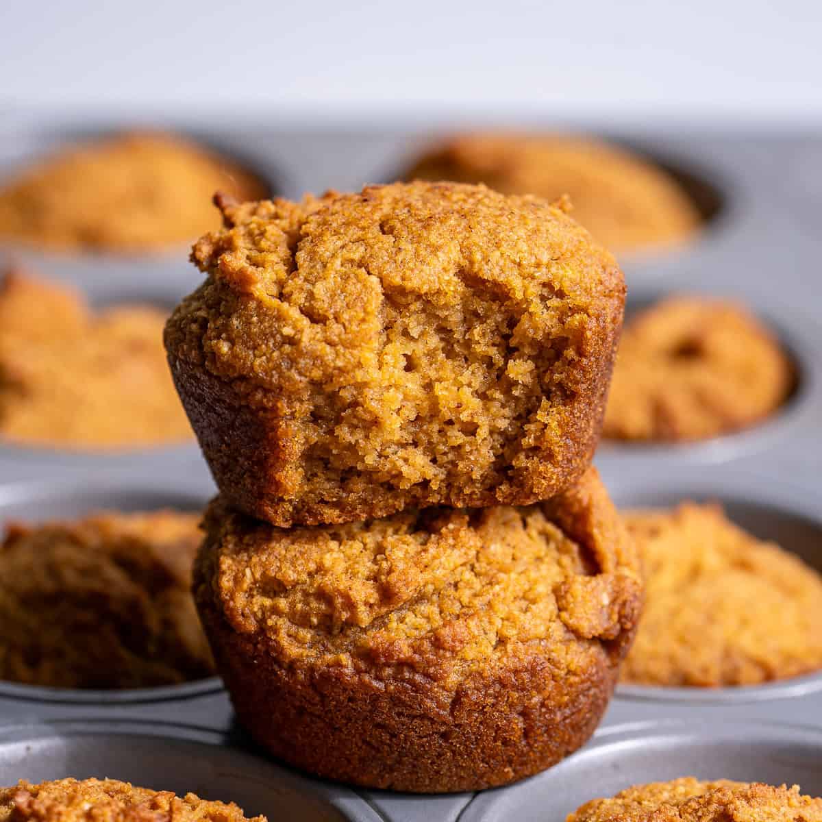 A close up of two almond flour pumpkin muffins showing the soft inner and outer textures of the muffins.