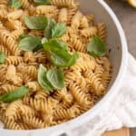 A pan of lemon garlic pasta topped with fresh basil leaves.