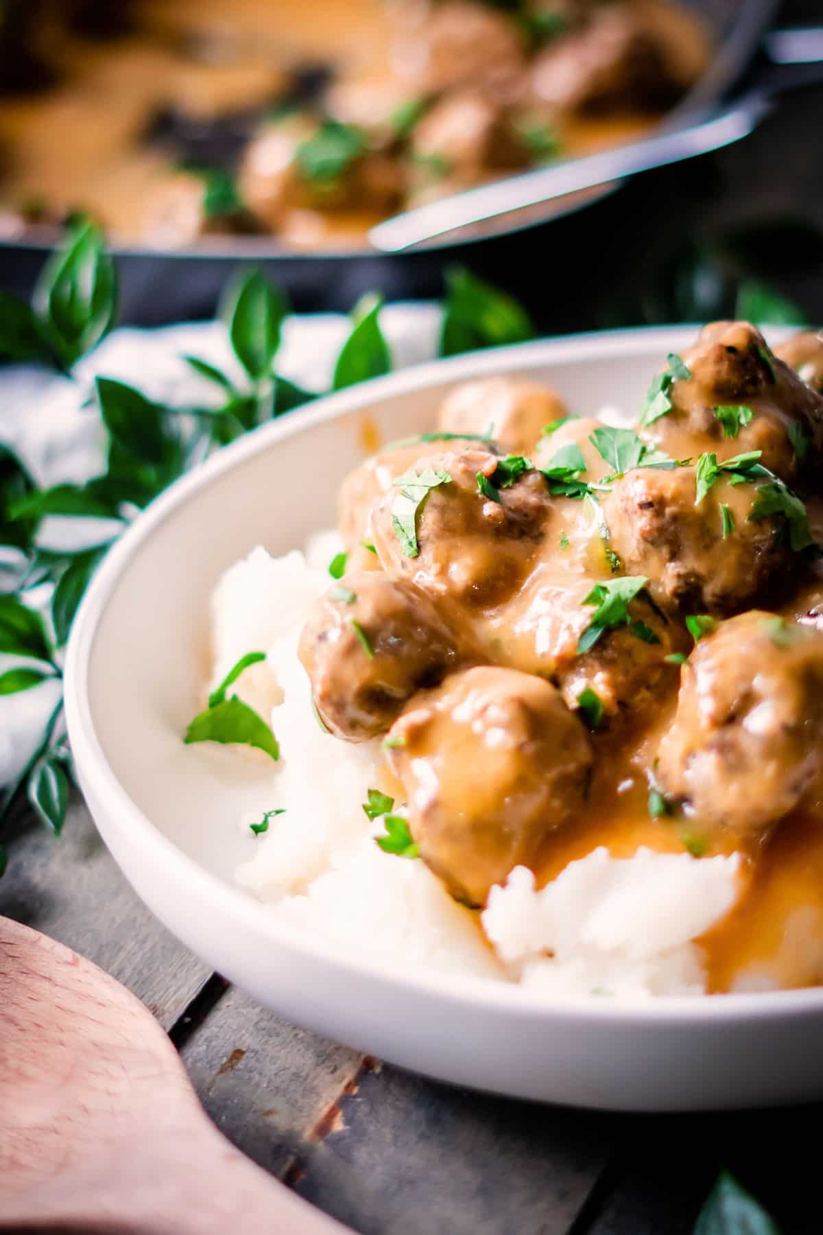 A serving bowl of mashed potatoes topped with dairy-free Swedish meatballs.