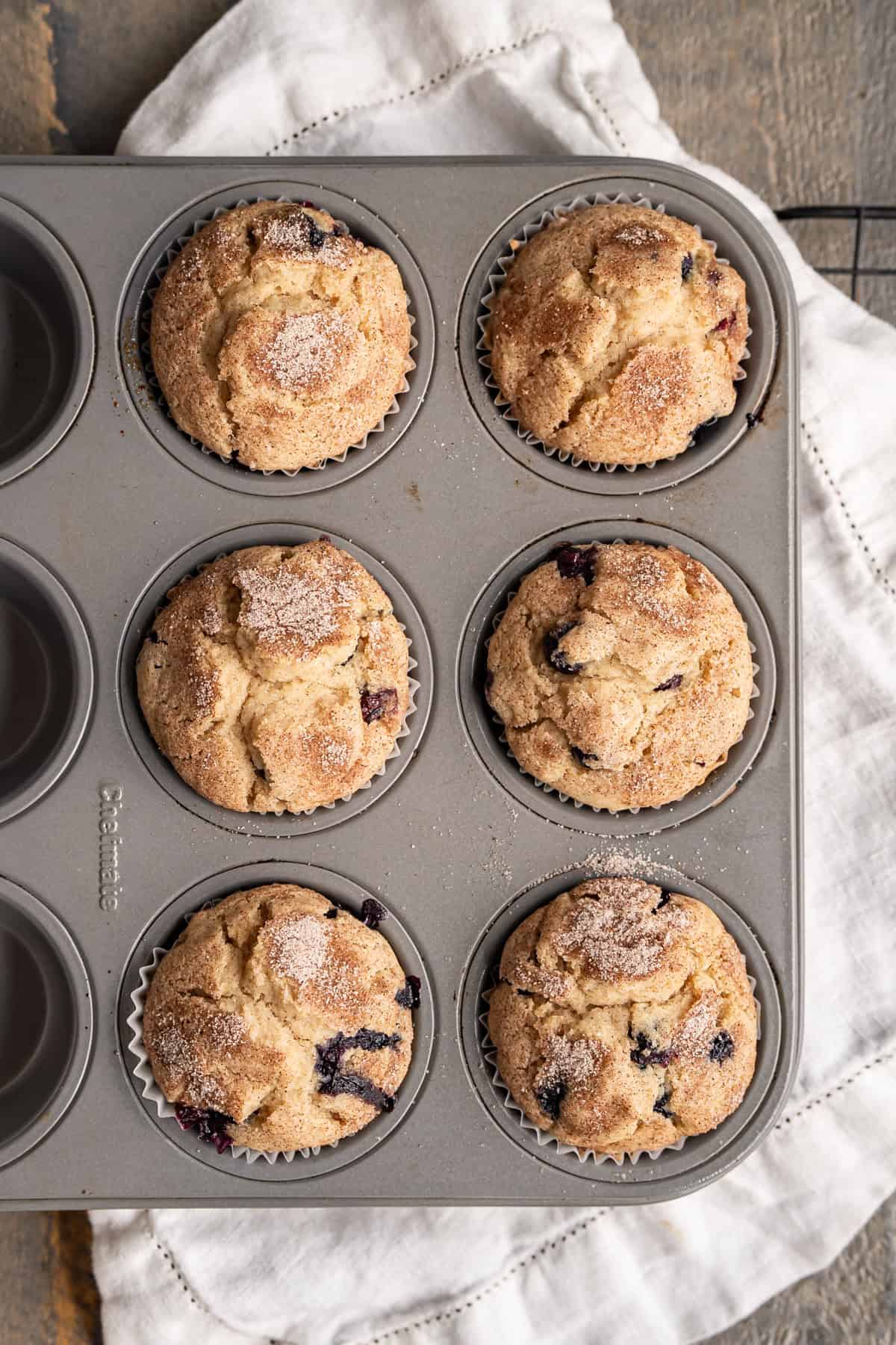 Six freshly baked gluten-free blueberry muffins with cinnamon sugar on top.
