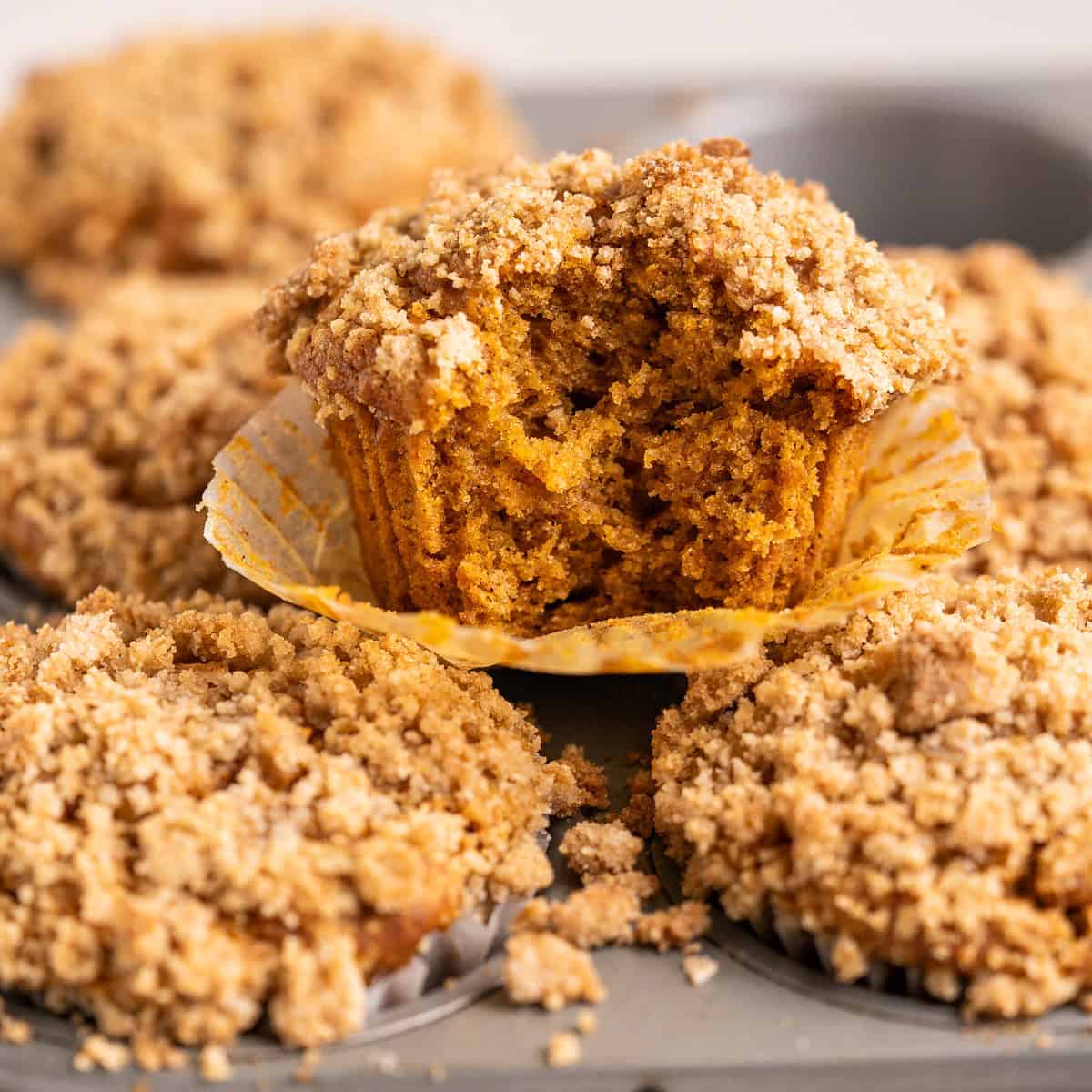 The inside of a gluten-free vegan pumpkin muffin to show the layers of moist pumpkin muffin and crisp streusel topping.
