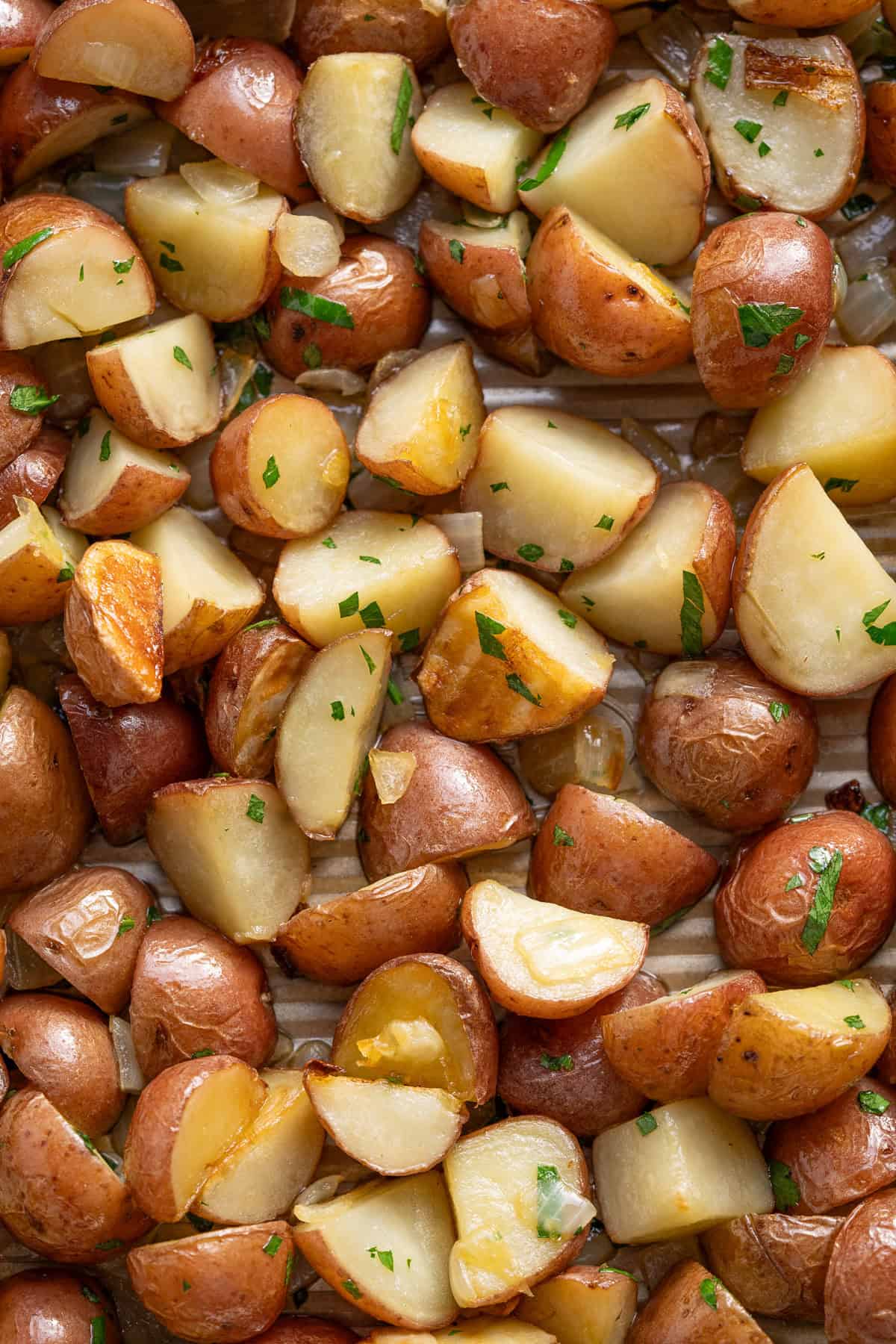 Freshly baked parsley roasted potatoes on a baking tray.