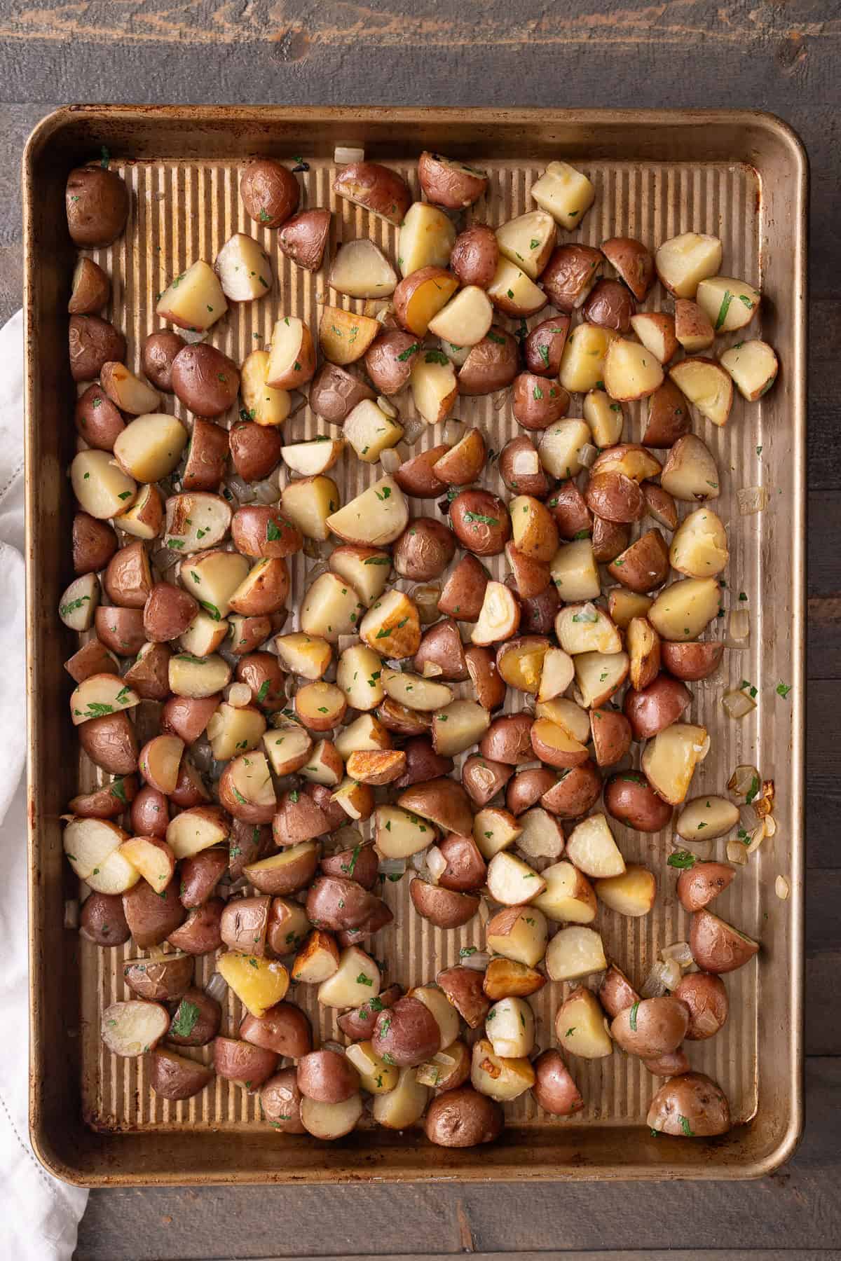 A baking pan filled with of quartered oven roasted parsley new potatoes.