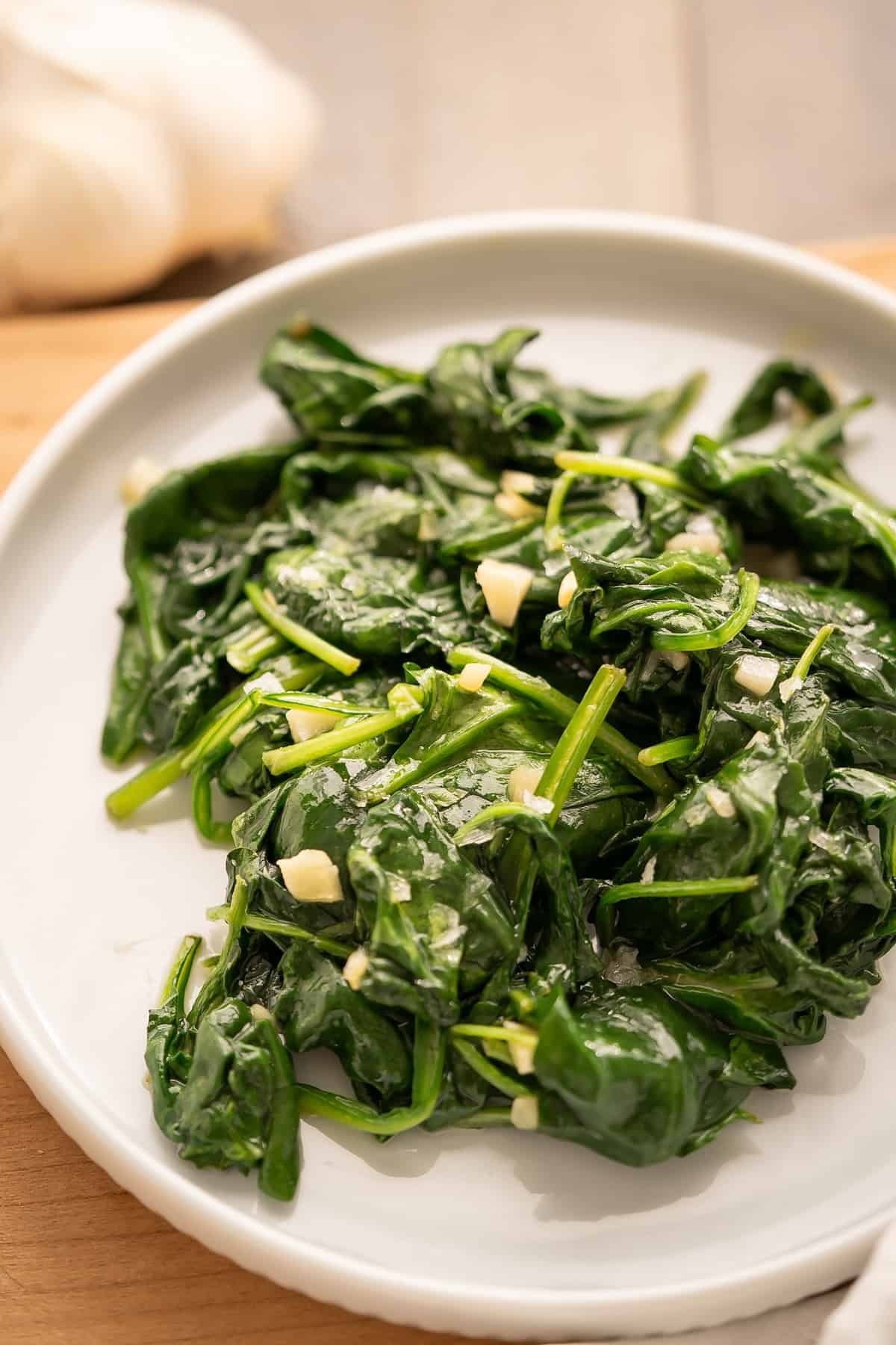 A close up of sauteed garlic spinach showing pieces of garlic amongst the wilted spinach.