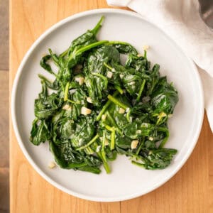 A plate of sautéed garlic spinach flecked with flaky sea salt.