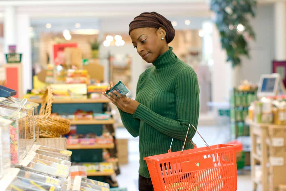 A woman reading food labels in the grocery store.