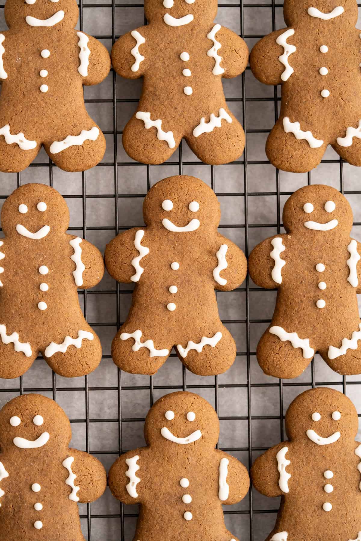 A cooling rack of gingerbread men decorated with vegan royal icing.