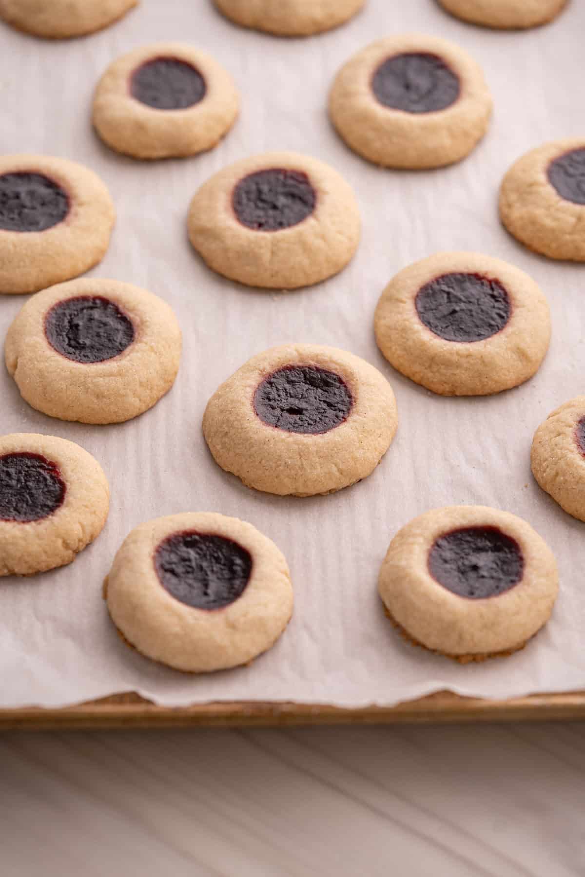 A baking sheet with a freshly baked batch of gluten-free thumbprint cookies.