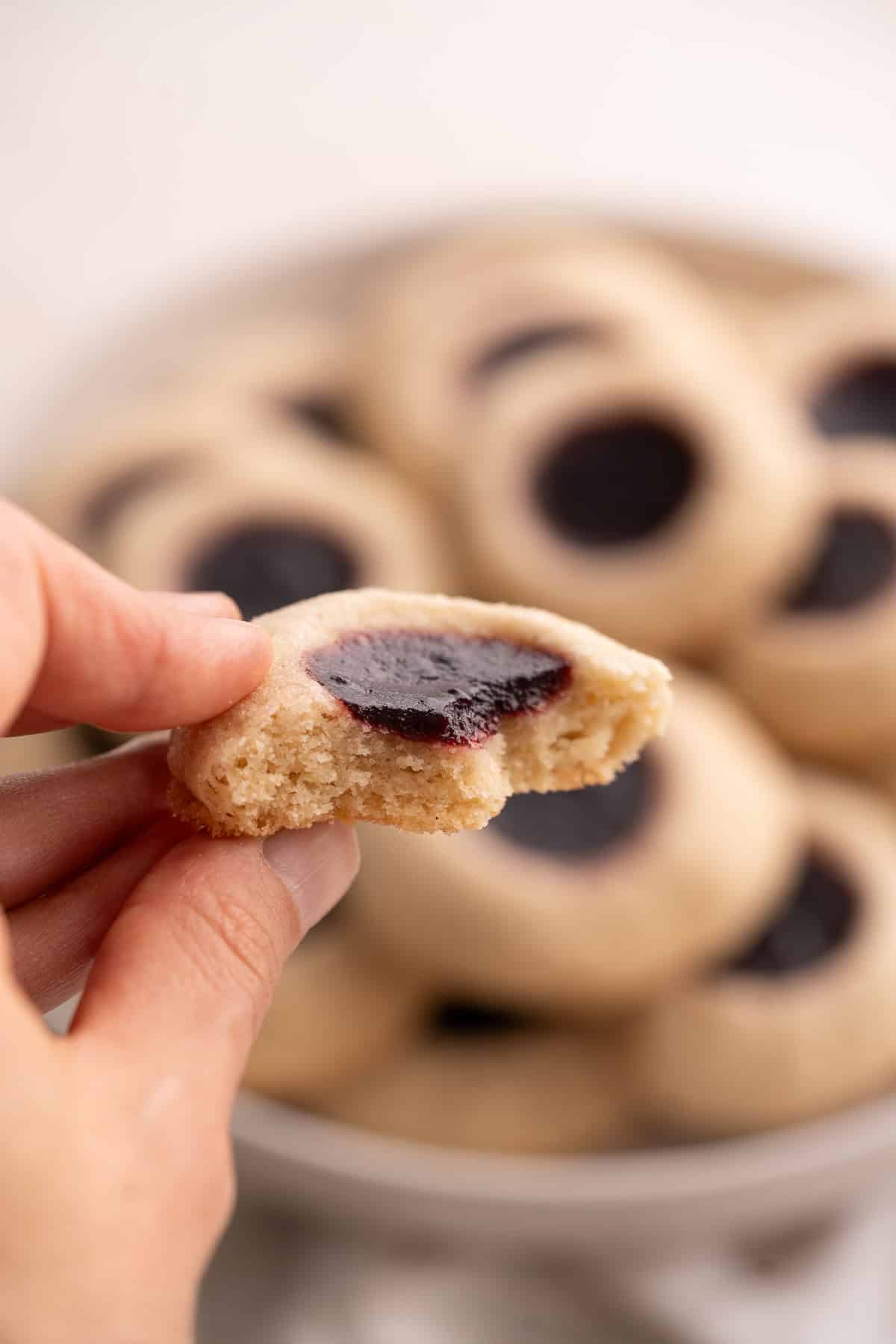 The inside of a gluten-free thumbprint cookie to show the moist interior and thick blackberry jam layer.
