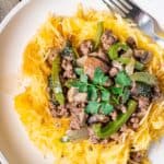 Spaghetti squash noodles topped with ground beef, green peppers, and mushrooms with a drizzle of balsamic vinegar.