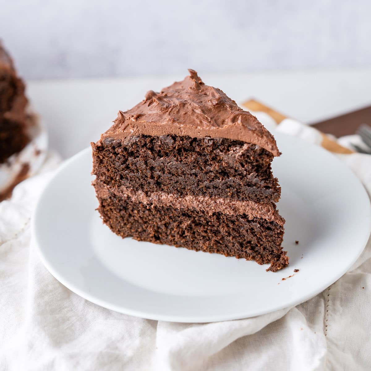 A large slice of vegan gluten-free chocolate cake made with almond flour and gluten-free flour with vegan chocolate frosting.
