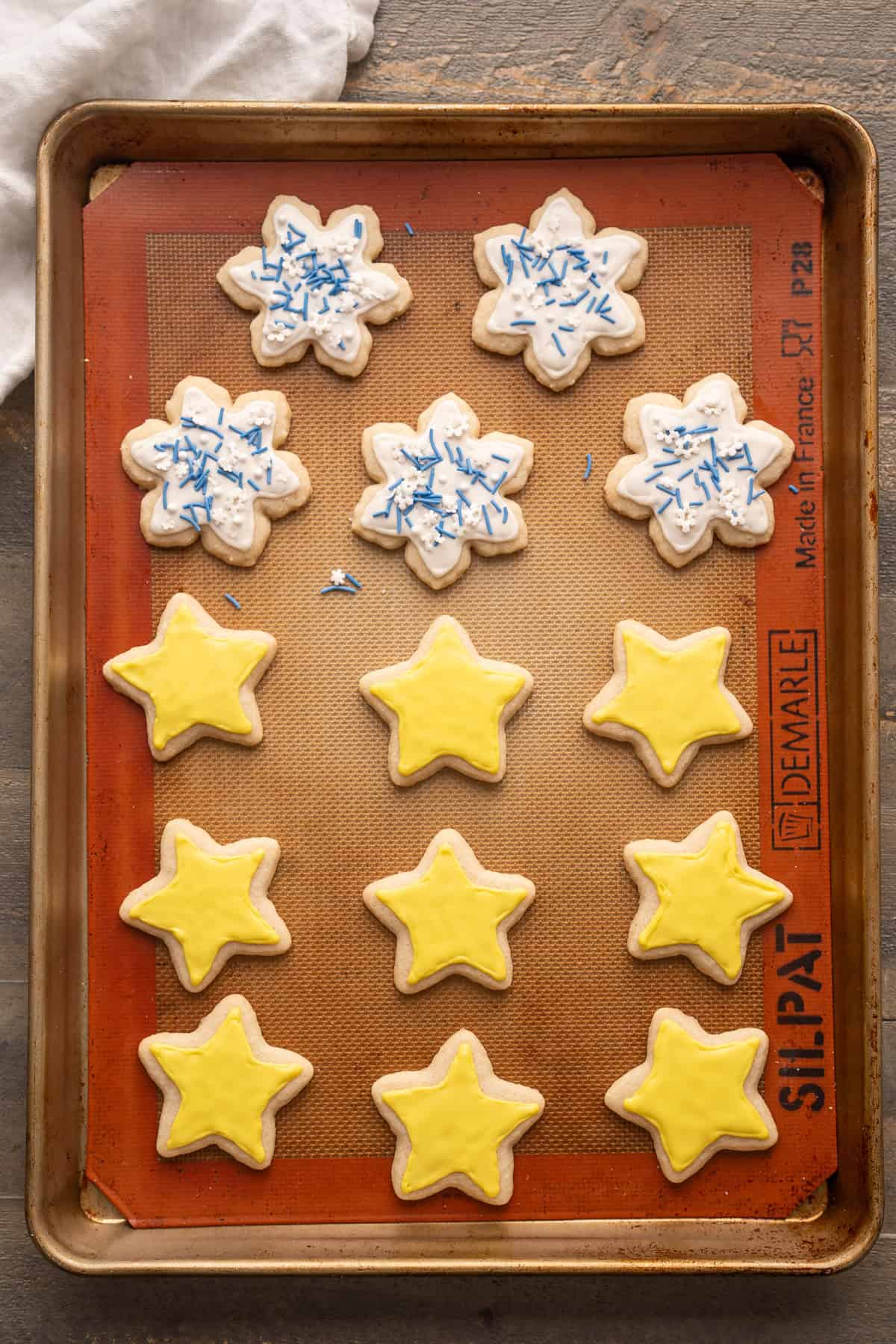 A tray of sugar cookies decorated with white and yellow vegan royal icing.
