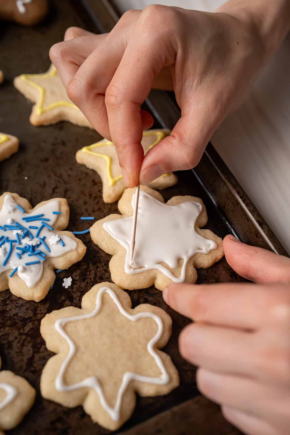 Using a toothpick to spread vegan royal icing inside a previously outlined design.