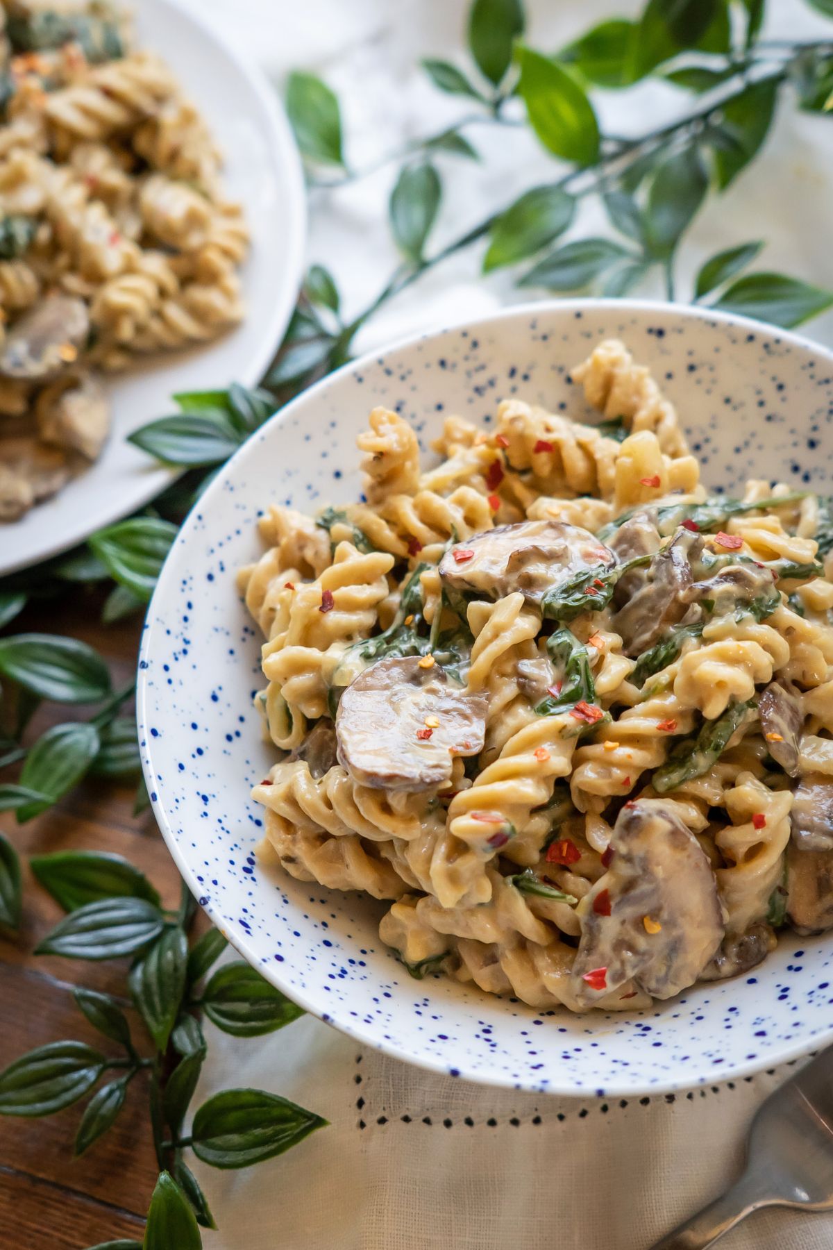 A bowl of creamy vegan mushroom pasta with fusilli pasta and chunky mushroom slices smothered in a creamy golden sauce.