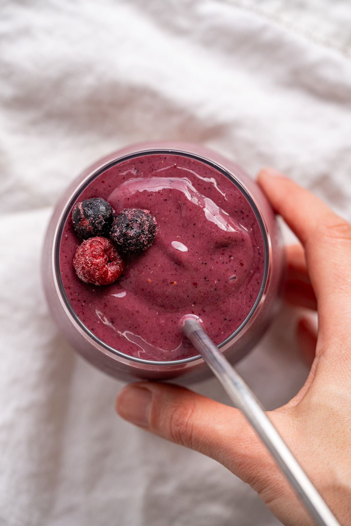 A bluish purple mixed frozen fruit smoothie with frozen berries to garnish.
