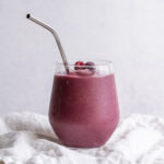 A mixed frozen fruit smoothie with a gorgeous purple color in a jar with a straw.