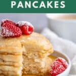 A stack of four fluffy gluten-free pancakes with maple syrup and fresh raspberries.