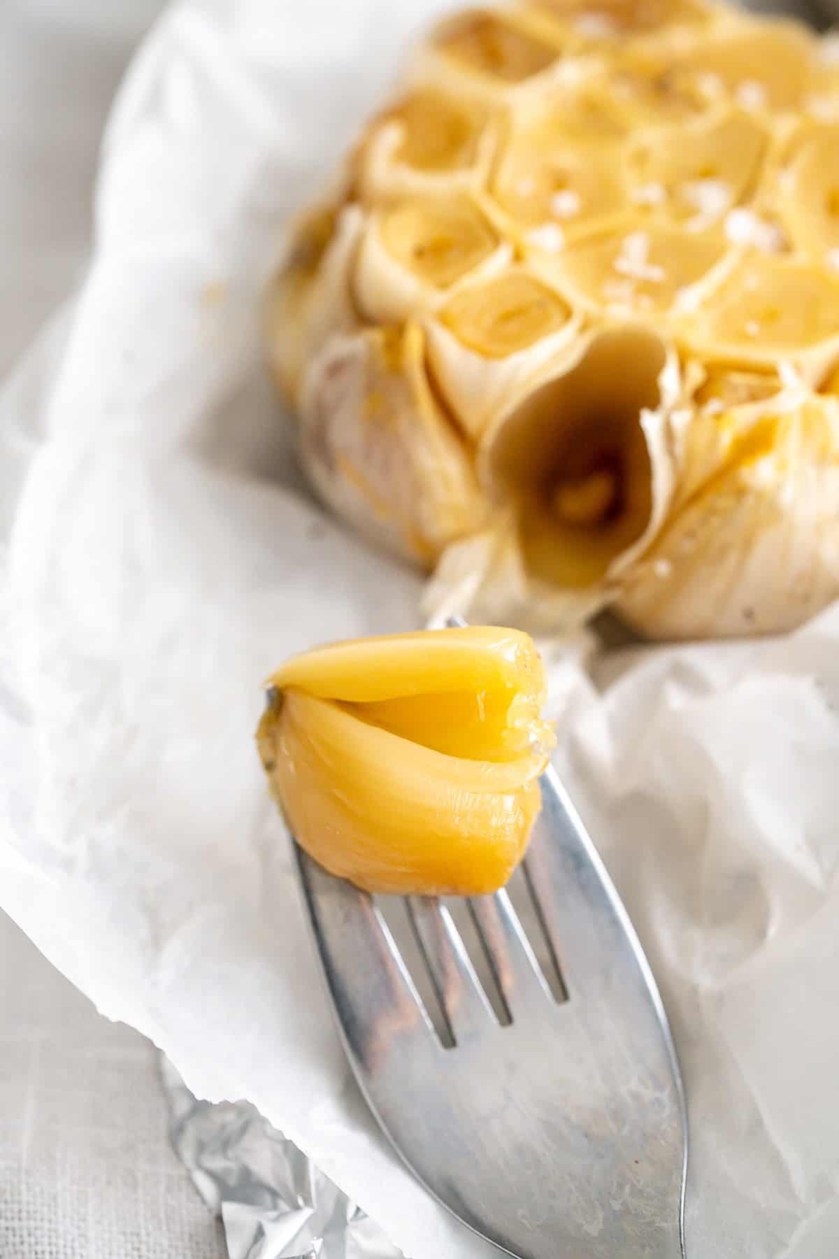 A roasted garlic clove on a fork.
