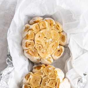 Roasted garlic heads nestled in parchment paper and foil.