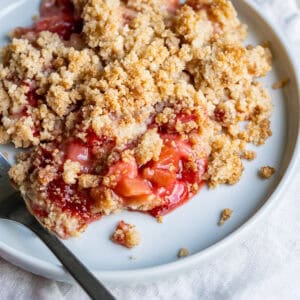 A piece of strawberry rhubarb crumble showing the layers of sweet glazed filling and crispy crumble topping.