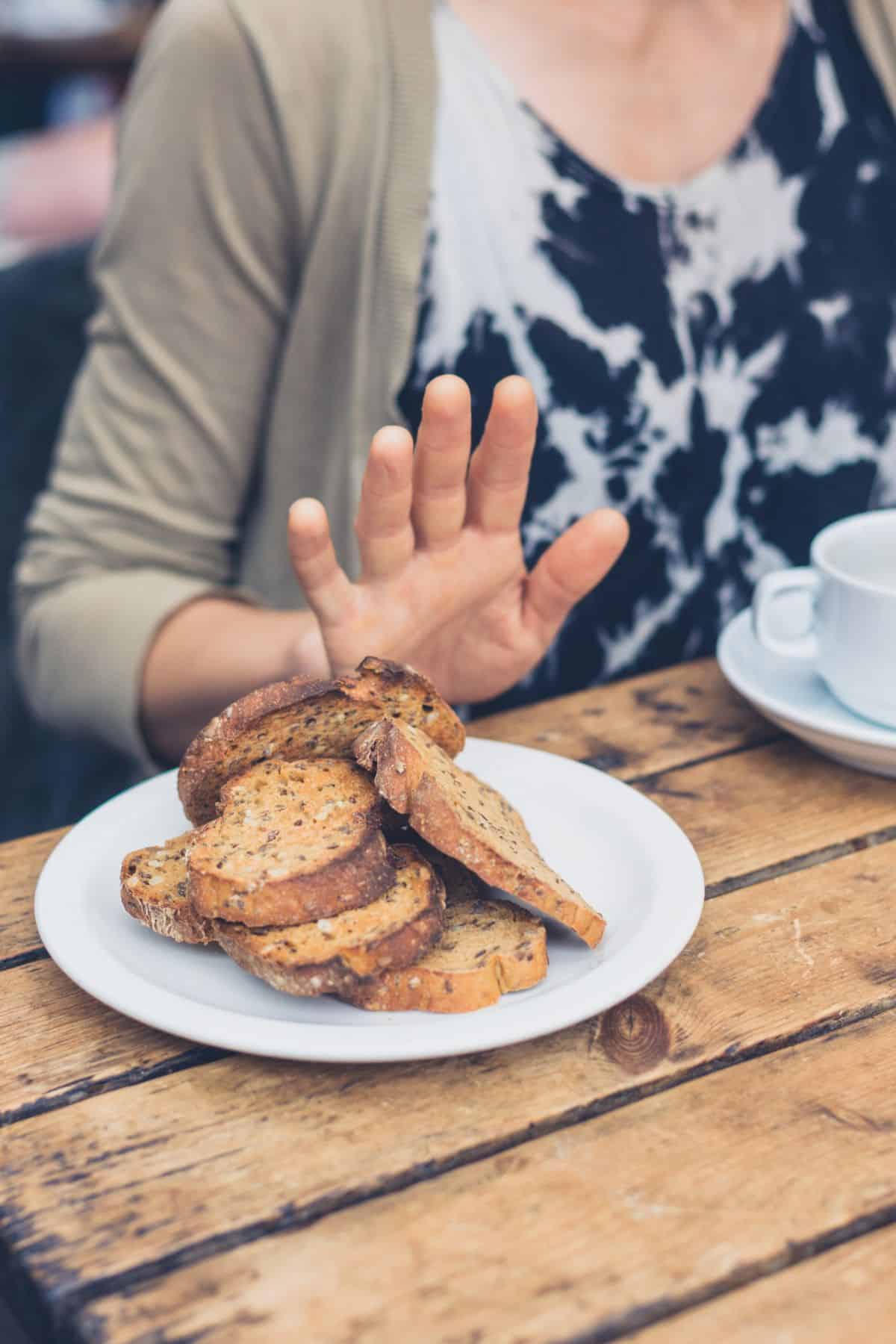 A hand pushing wheat bread away.