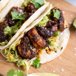 The inside of blackened shrimp tacos featuring avocado slaw, shrimp, cilantro, and flaky sea salt.