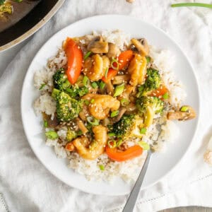 A plate of shrimp stir-fry over a bed of white rice.